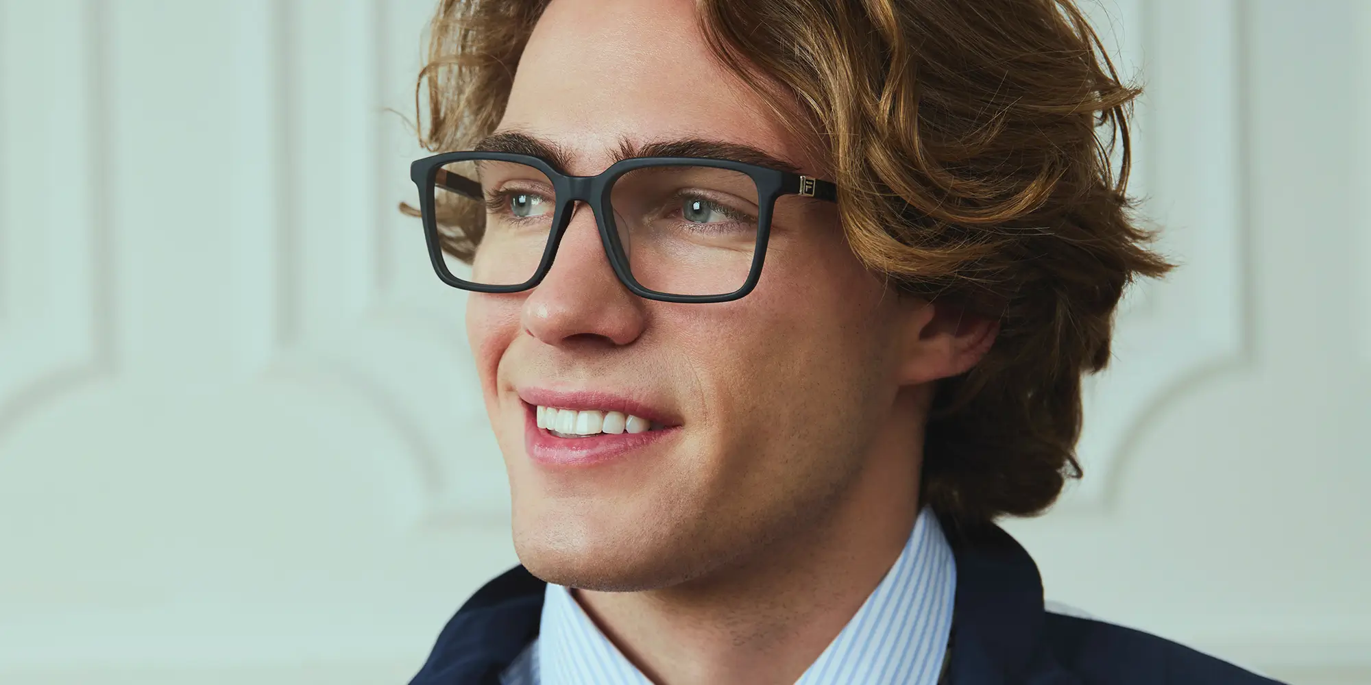 Man lying down in eyeglasses, looking up with head resting on a racket.